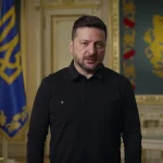 Президент Владимир Зеленский в кабинете на фоне государственного герба Украины