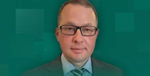 Чоловік у окулярах сірому костюмі та смугастому галстуку на зеленому фоні